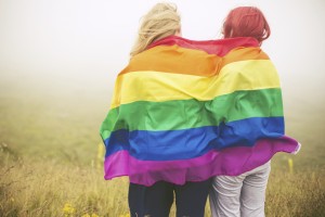 Blonde and redhead woman wrapped in rainbow flag